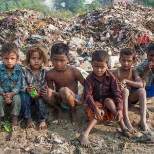 impoverished children sitting by littered roadside