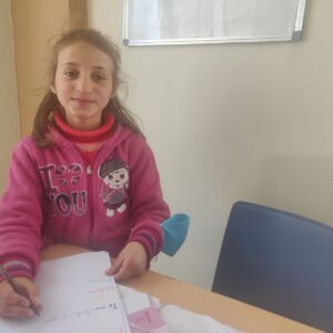 child writing at Global Care Albania's school club