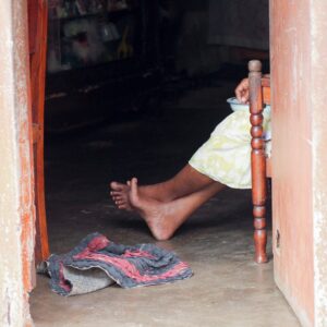 bare feet of Sri Lankan woman in darkened doorway of shack home