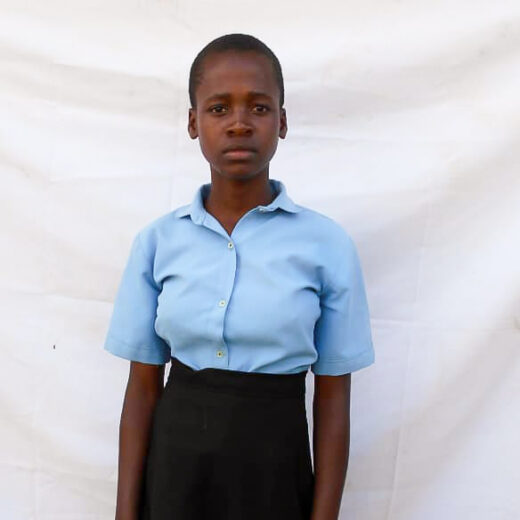 A teenage girl in Malawi looks into the camera. She is wearing school uniform.